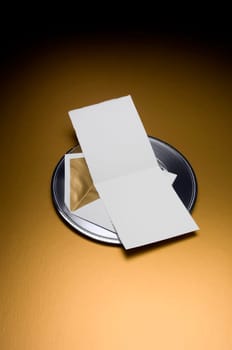 Image of a Blank Invitation with envelop on silver tray and gold background