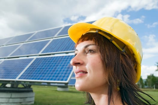 Side head portrait of a young brunette woman with yellow construction helmet as a headgear and optimistic view to the side