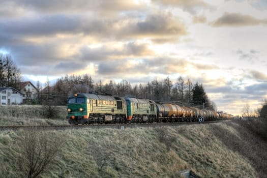Freight train hauled by two diesel locomotives passing the fields