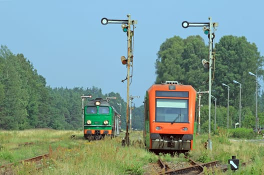 Diesel locomotive and light railbus crossing at the station