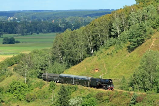 Beautiful hilly landscape with an old retro steam train