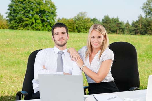Young business colleagues in nature office sitting behind table portrait