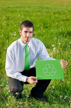 Green energy - Young businessman in sunny meadows hold recycling sign