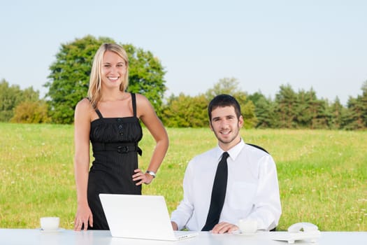 Young businessman in sunny nature have coffee with female colleague