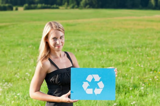 Green energy - Young businesswoman in sunny meadows hold recycling sign