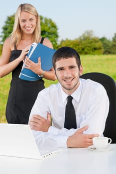 Young businessman in sunny nature with folders and female colleague