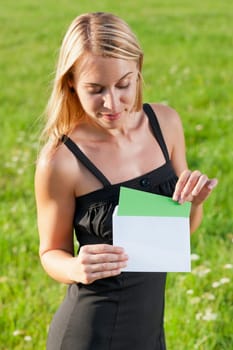 Surprise envelope young attractive businesswoman opening letter sunny meadow