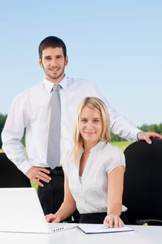 Young business colleagues in nature office smile behind table