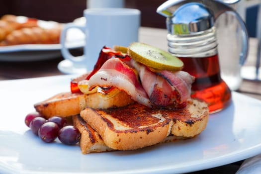 Closeup image of a French toast with bacon and garnish