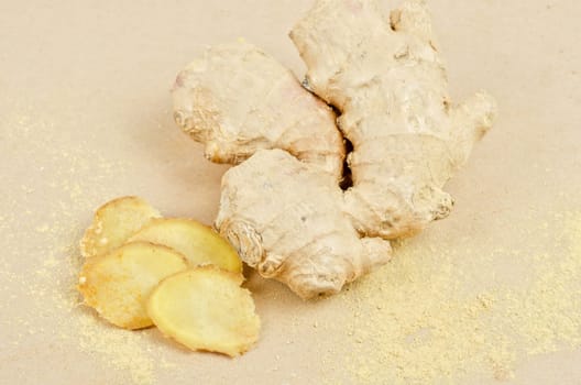 Fresh, dried and powdered ginger at brown background