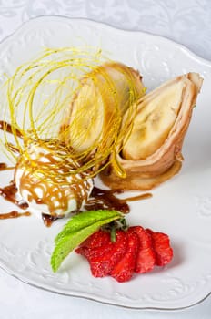 Dessert of pancake with banana, ice-cream, caramel, strawberry and mint