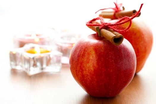 Close-up of delicious red Christmas apples with cinnamon sticks and candles