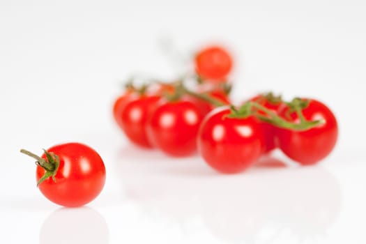 Cherry tomatoes on a stick with oil and pepper on a white background