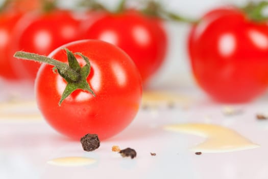 Cherry tomatoes on a stick with oil and pepper on a white background