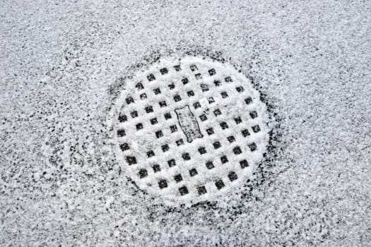 a snow covered manhole cover on the road surface