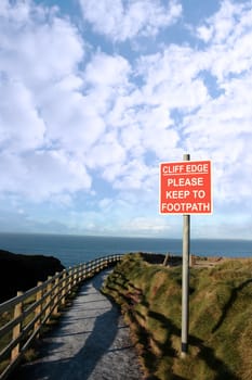 a warning sign of danger at a slippery cliff edge walk