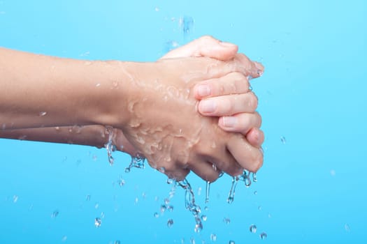 Woman washing her hands. Blue background.