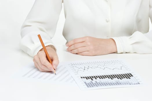 Woman business analyst - hand with pencil writing in sheet and graph