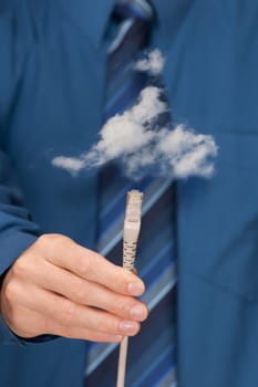 Cloud computing concept. Mans hand with ethernet cable connecting into cloud. Selective focused on cable.