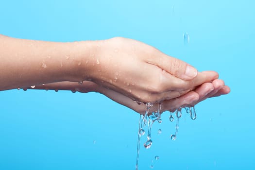 Woman washing her hands. Blue background.