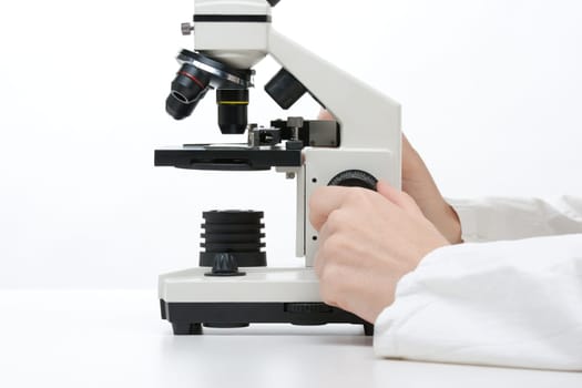 Female researcher with microscope. Focused on microscope and hands.