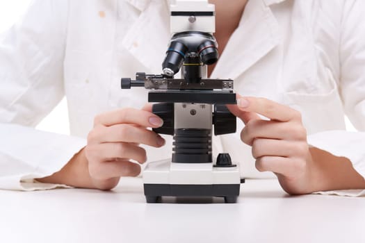 Female researcher with microscope. Focused on microscope and hands.