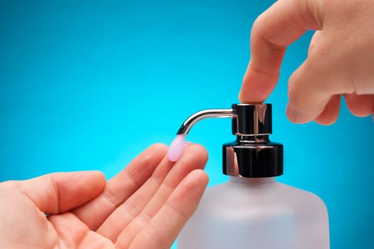 Man washing his hands with liquid soap. Blue background.