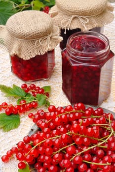 Jars of homemade red currant jam with fresh fruits