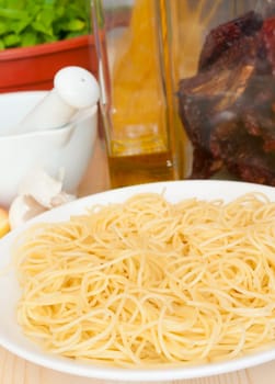 Italian Cuisine - spaghetti, dried tomatoes, pecorino cheese, garlic, basil, mortar with pestle and olive oil