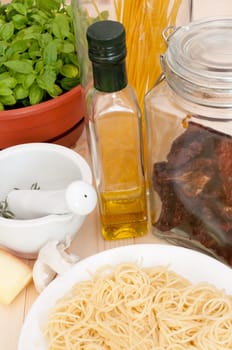 Italian Cuisine - spaghetti, dried tomatoes, pecorino cheese, basil, garlic, mortar with pestle and olive oil