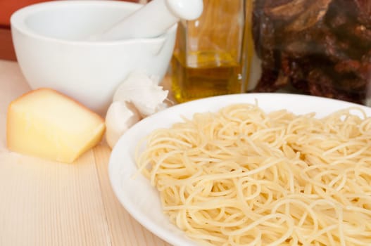 Italian Cuisine - spaghetti, dried tomatoes, pecorino cheese, garlic,  mortar with pestle and olive oil