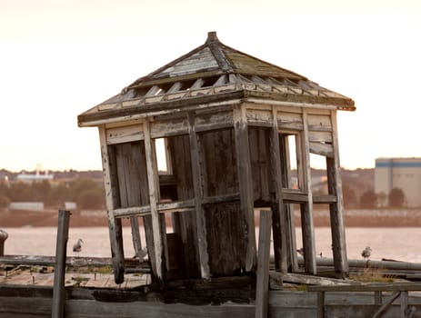Collapsing shelter on pier by the side of the Mersey in Liverpool at sunset