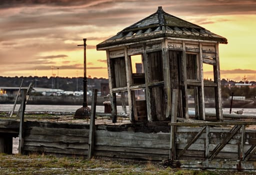 Collapsing shelter on pier by the side of the Mersey in Liverpool at sunset