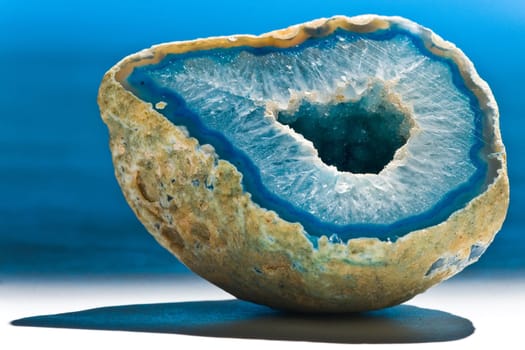 Piece of blue shiny agate with hole on white background