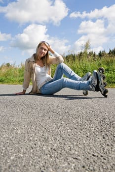 Inline skates young attractive woman wearing jeans sitting asphalt road