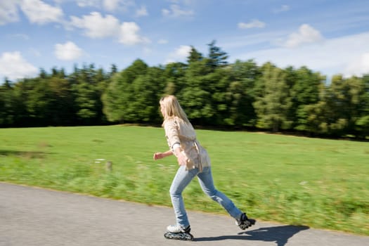 Inline skating young woman speed workout sunny asphalt road