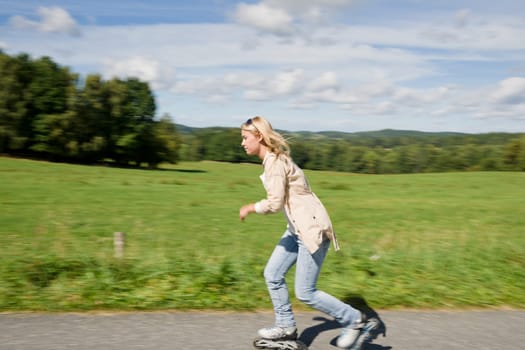 Inline skating young woman speed workout sunny asphalt road