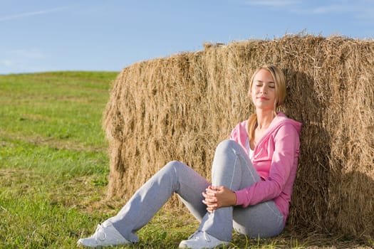 Sportive young woman relax lean against hay bales sunset countryside