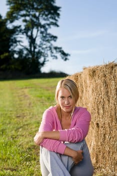 Sportive young woman relax lean against hay bales sunset countryside
