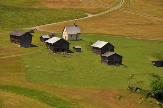 landscape with mountain huts and small chapel in swiss alpine valley