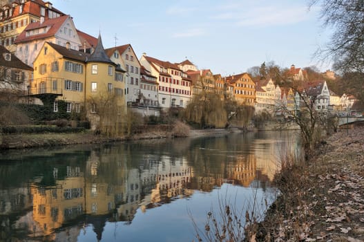 view of a row of ancient buildings with colored facades on river embankment in city center, shot in winter light