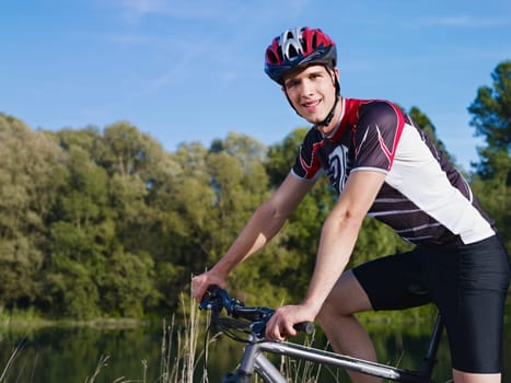 sports activity: young adult cyclist riding mountain bike in the countryside and looking at camera. Horizontal shape, side view, copy space
