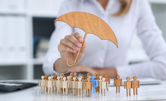 The female hand holds a miniature umbrella in the hand of the topic of liability insurance