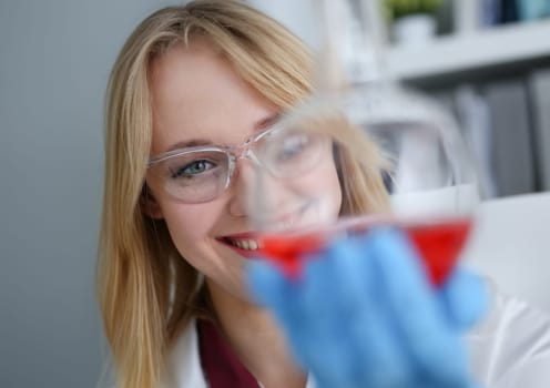 Technician hold in arms in protective gloves sample bottle with poison fluid portrait. Medical worker in uniform use reagent tube for virus infection exam or biological toxic reaction drug creation