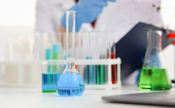 Chemical industry bulb with blue magenta pink liquid lab tubes stand on the table in the laboratory. Of liquid testing test development substances poisons additives stabilizers flavors house cleaning.