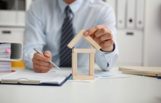Male hand holds the roof to the lock in the hand against the backdrop of the toy house sale. Purchase lease concept real estate services on the market.