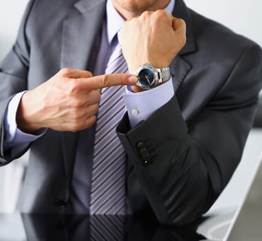 Man in suit and tie check out time at silver wristwatch closeup. Show and point with finger waste minute modern punctual life style start hurry job idea last second clockwork precision concept