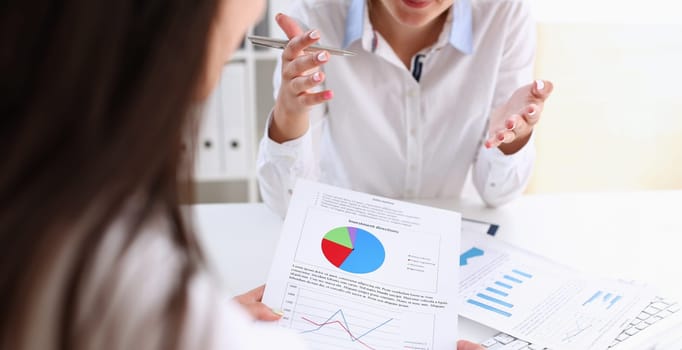 Businesswoman holding a silvery pen in her hand indicates the interlocutor for a diagram on the form. Of annual report on the financing of organizations trains the processing of this statistical study.