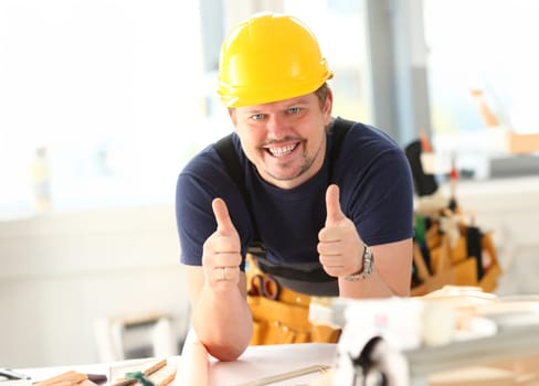 Smiling worker in yellow helmet show confirm sign with thumb up at arm portrait. Manual job DIY inspiration joinery startup idea fix shop hard hat industrial education profession career concept