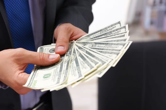 Man in suit and tie hold in arm pack of hundred dollar bills closeup. Stock market exchange earn pile rich present gift employer prepayment service gratitude concept